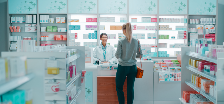A lady is stood at the pharmacy counter to collect her emergency prescriptions