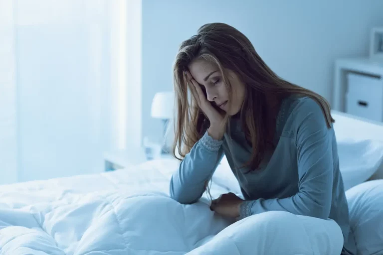 Women fatigued sat in bed with head in hand