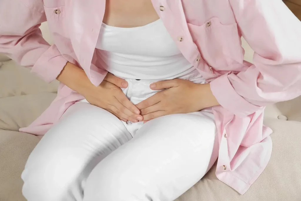 A woman holds her tummy in pain caused by a UTI