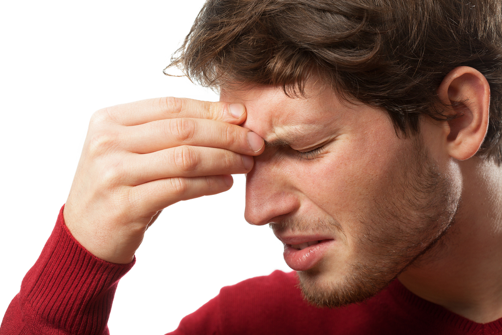 A man pinches his forehead in pain caused by a migraine