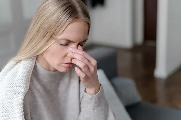 A woman holds her nose due to pain caused by sinusitis