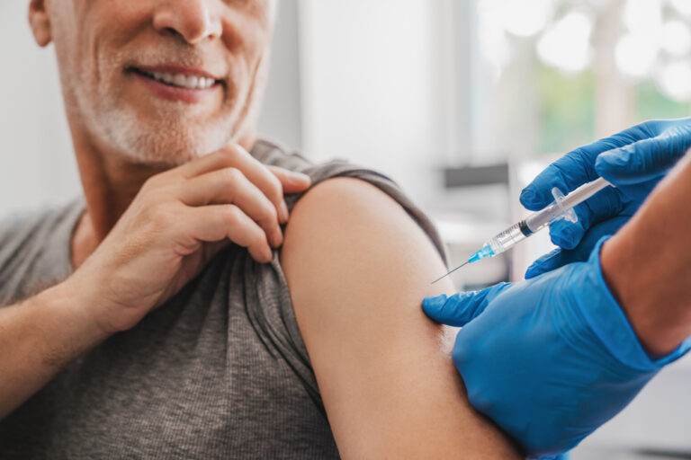 An older male receives a vaccination jab in the arm