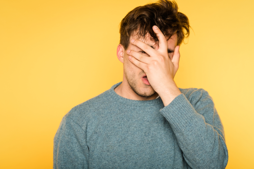 A young man covers his face in embarrassment due to having a random erection.