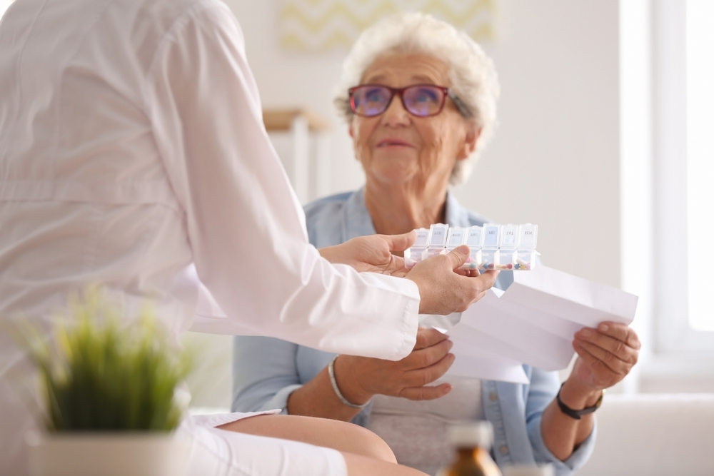 An older lady receives her medication from a pharmacist to help treat her arthritis pain