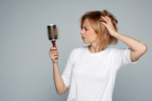 A young woman looks confused, her brush is full of hair, caused by a nutrient deficiency.