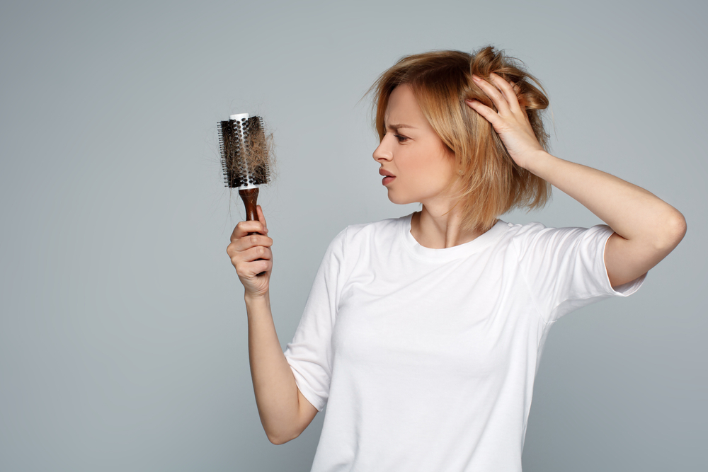 A young woman looks confused, her brush is full of hair, due to her contraception.