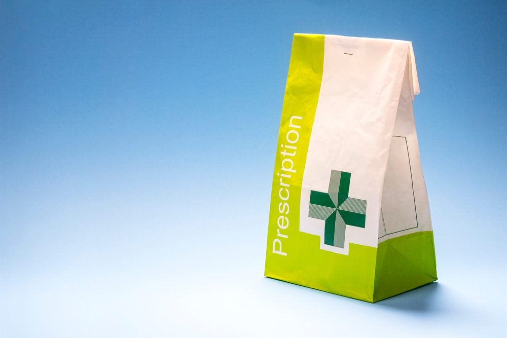 A photo of a white and green prescription bag containing a "prescription only" medication.