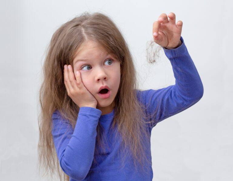 A child looks shocked at the clump of hair in their hand.