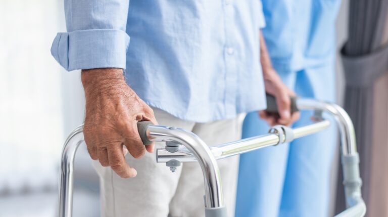 A man holds onto a zimmer frame due to multiple sclerosis (MS).