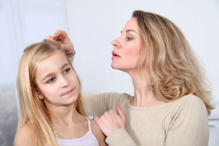 A woman examines her daughter's hair for head lice